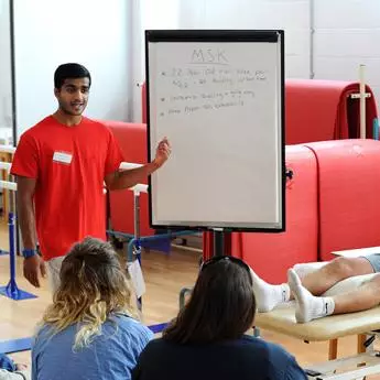 male physiotherapy student explaining case study on a board