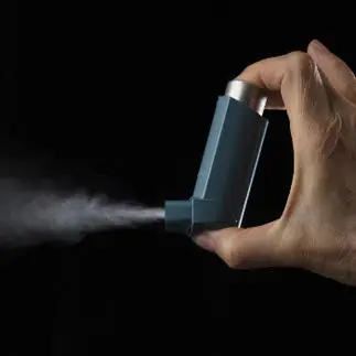 man spraying asthma inhaler