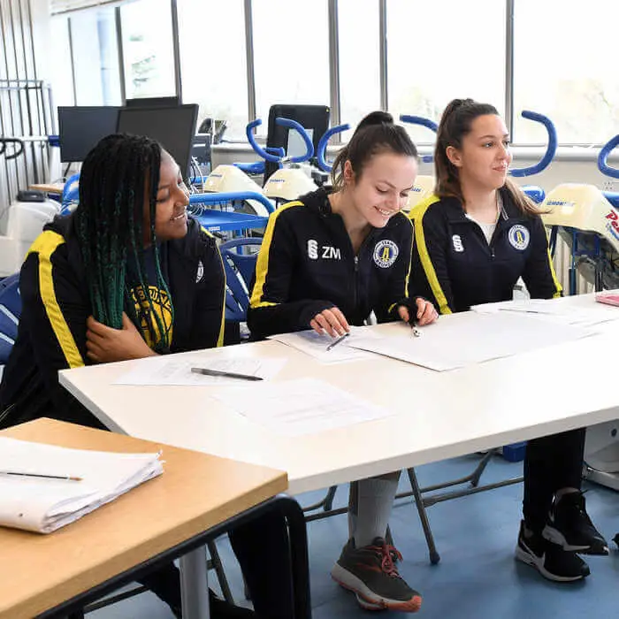 Group of sports students writing at a table