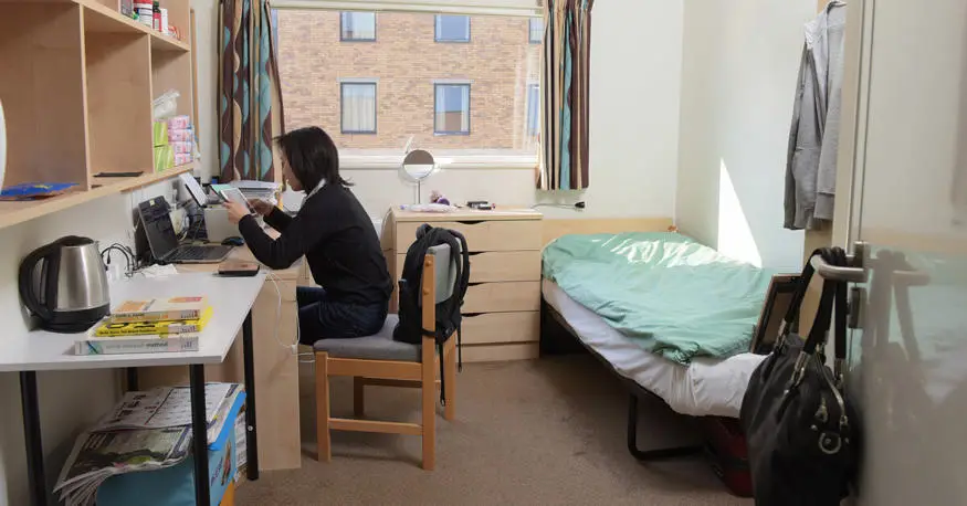 female student studying at her desk in student bedroom