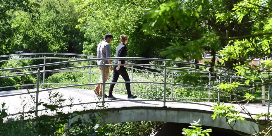 two students walking on campus across the bridge in summer