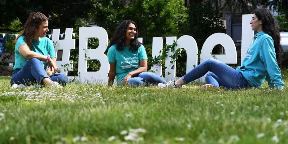 three brunel student ambassadors sat on the grass on campus