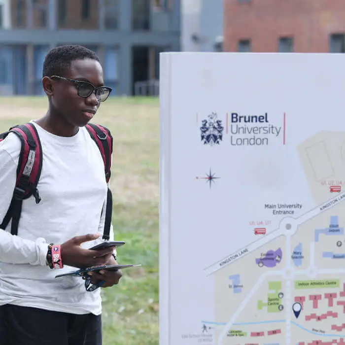 student walking by a campus map sign