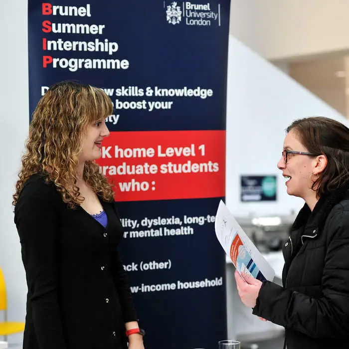 two people standing in front of a brunel summer internship sign