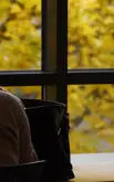 female student studying in library with autumn view in the background