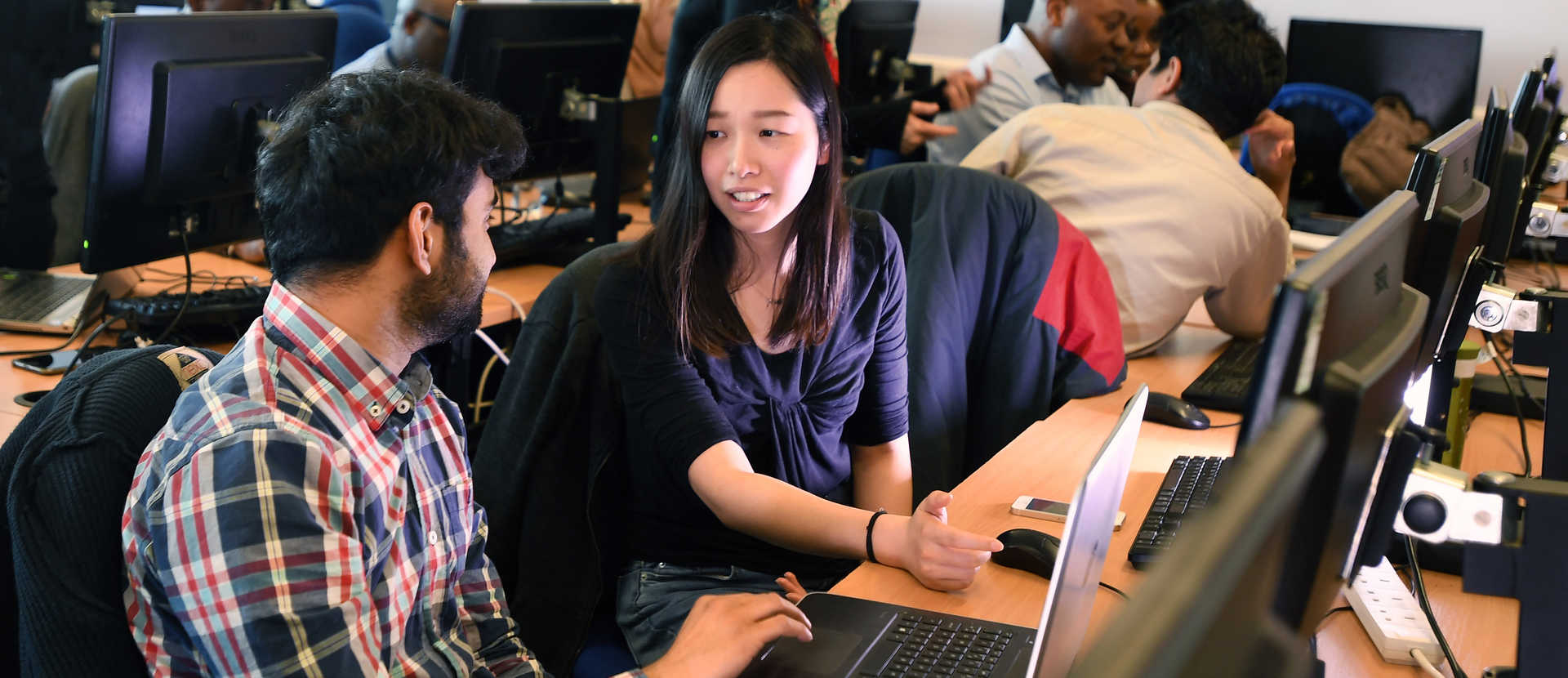 Students using a laptop and talking