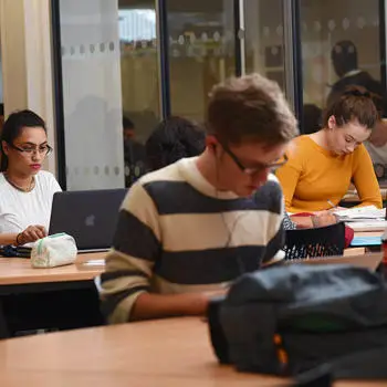 three students studying individually in the university library