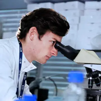 male student looking into a microscope in a laboratory