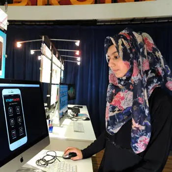 Woman standing on front of a computer and using the pc mouse