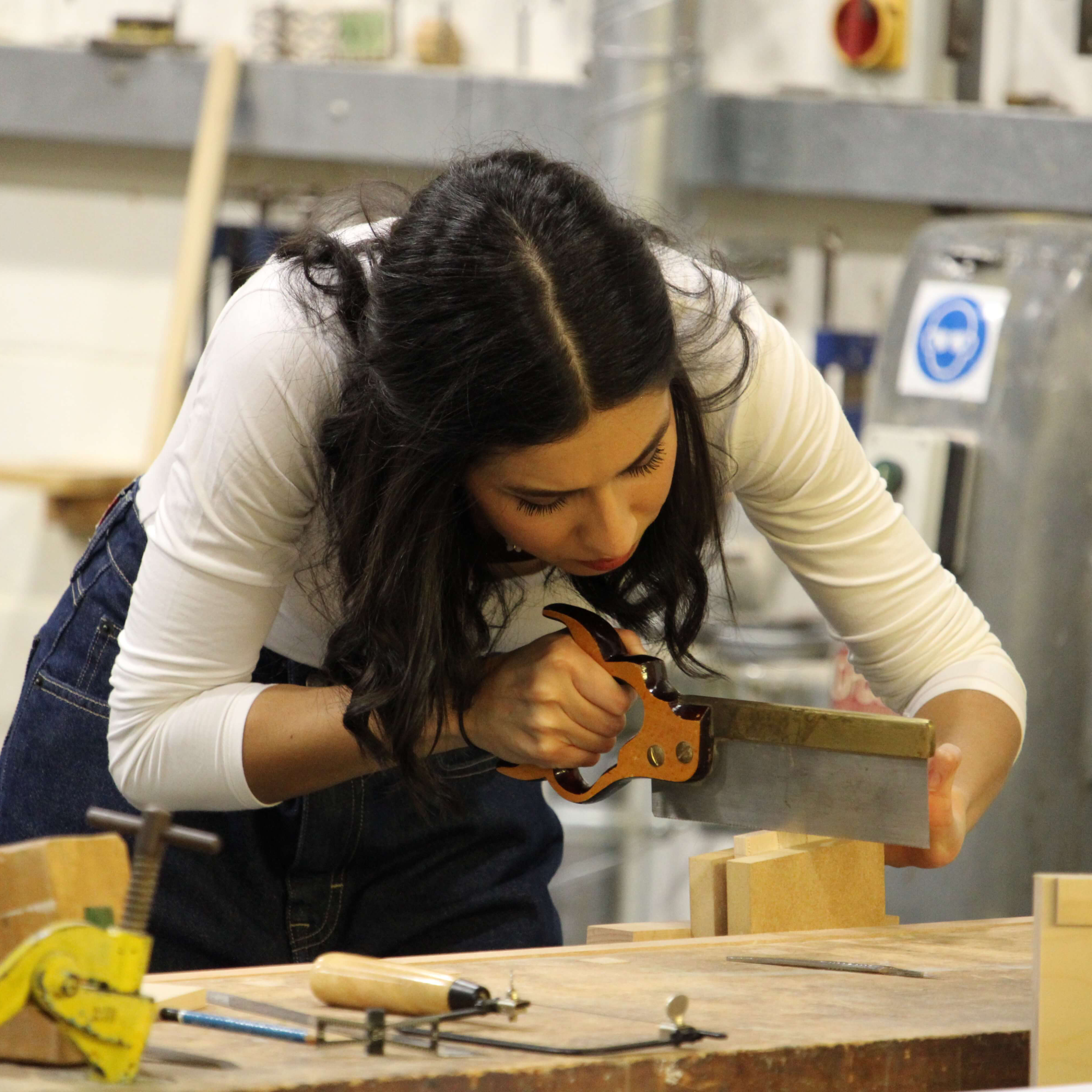 female student using saw in workshop