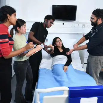A patient rests in a hospital bed while a diverse group of medical professionals engages in discussion and assessment