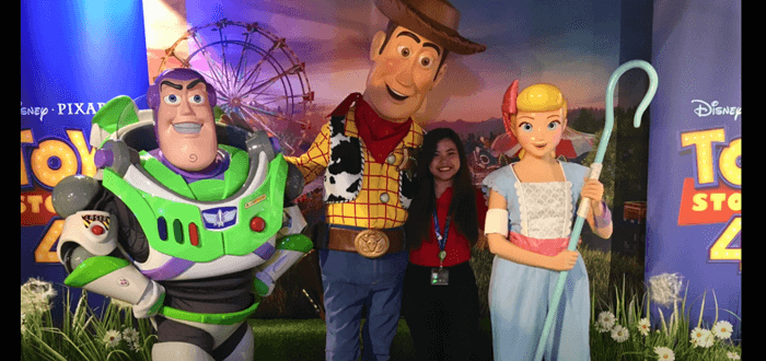 female student standing with disney characters woody, buzz and bo peep from toy story
