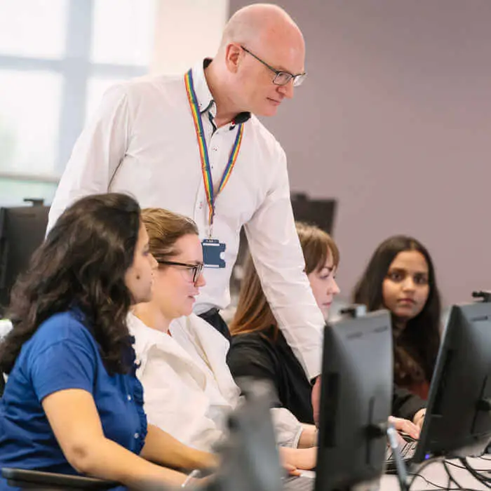 group of female students with male lecturer looking at computers