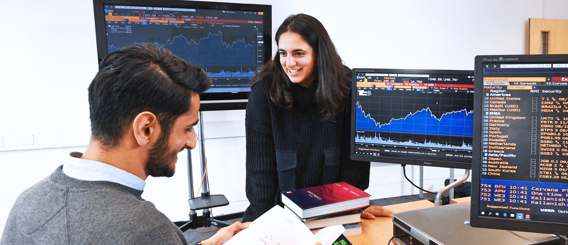 male and female student with computers displaying finance software