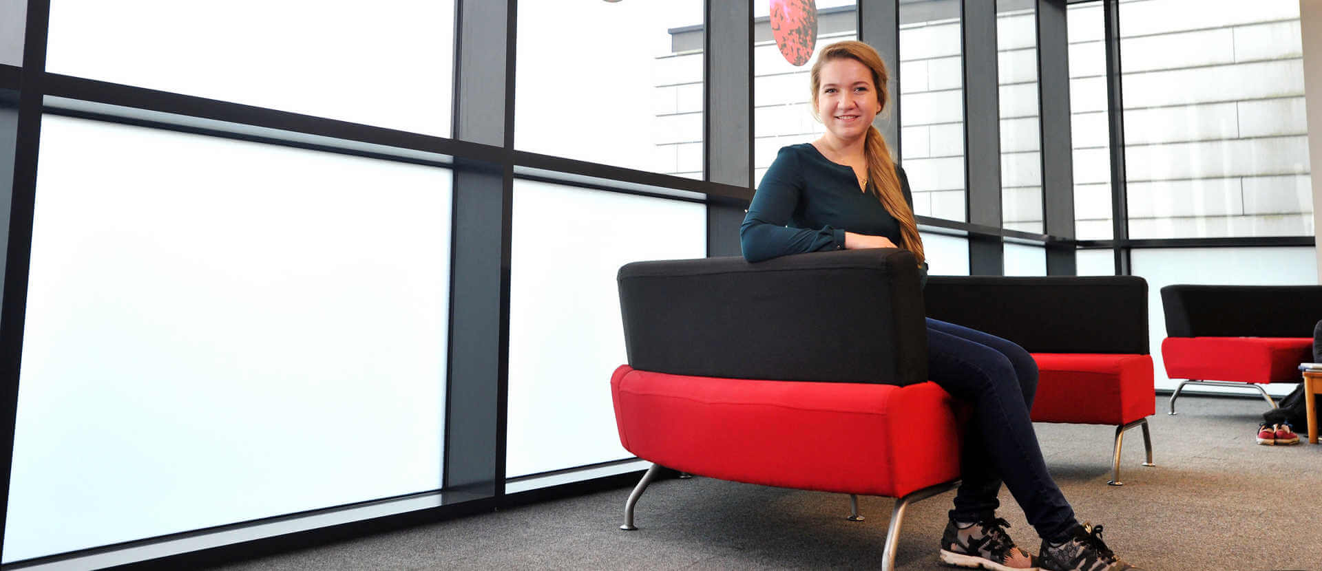 Economics and Finance undergraduate student poses on a red and black chair