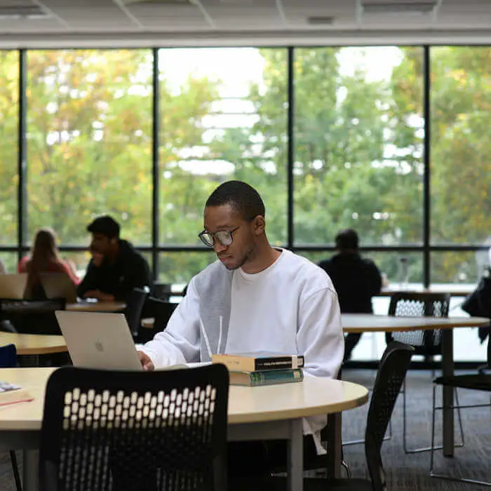 student at a desk with a laptop in a library