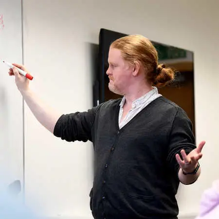 Brunel Univeristy London Games design lecturer writing on whiteboard and presenting to class