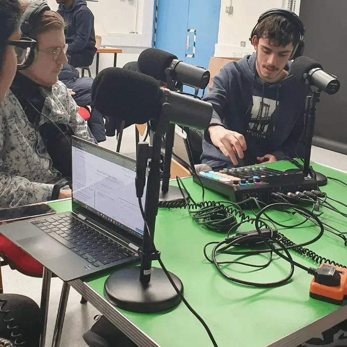 A-group-of-students-sit-around-a-table-with-microphones