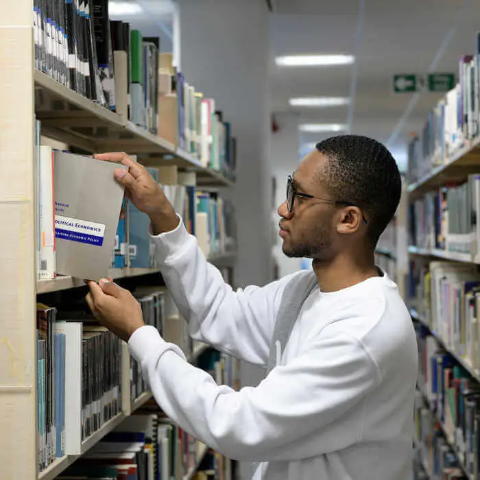 student placing book on a shelf in a library
