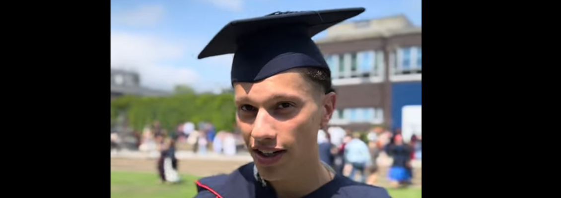Man in graduation hat and rob standing outside