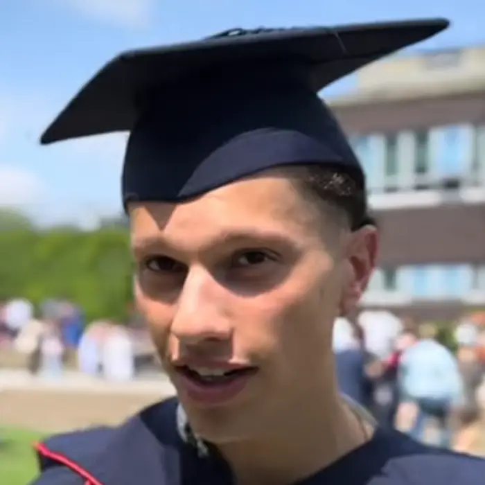 Man in graduation hat and rob standing outside