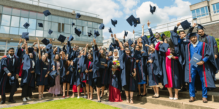 Group of graduates celebrating outdoors, throwing caps in the air