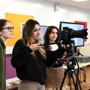 female film students standing and using a camera in a classroom