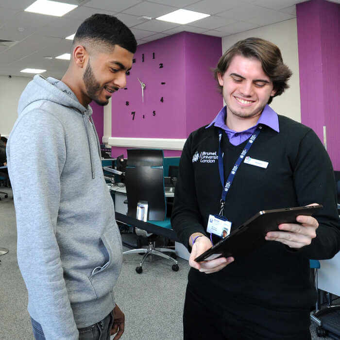 Two young men in an office, looking at a tablet together
