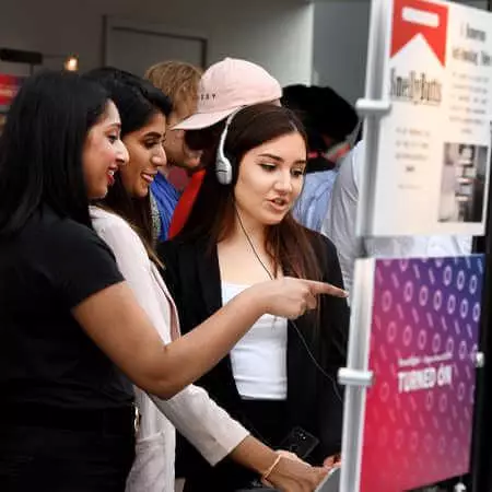 3 students looking at final year project at digital degree showcase