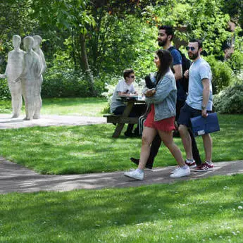 3 international students walking through green campus