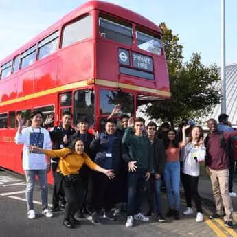Brunel students going on a trip and standing in front of a red London bus.