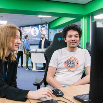 two students at a desk with screen and keyboard and mouse