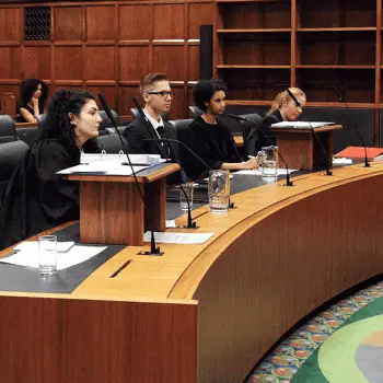 Group of students dressed in barister gowns sat behind a court desk