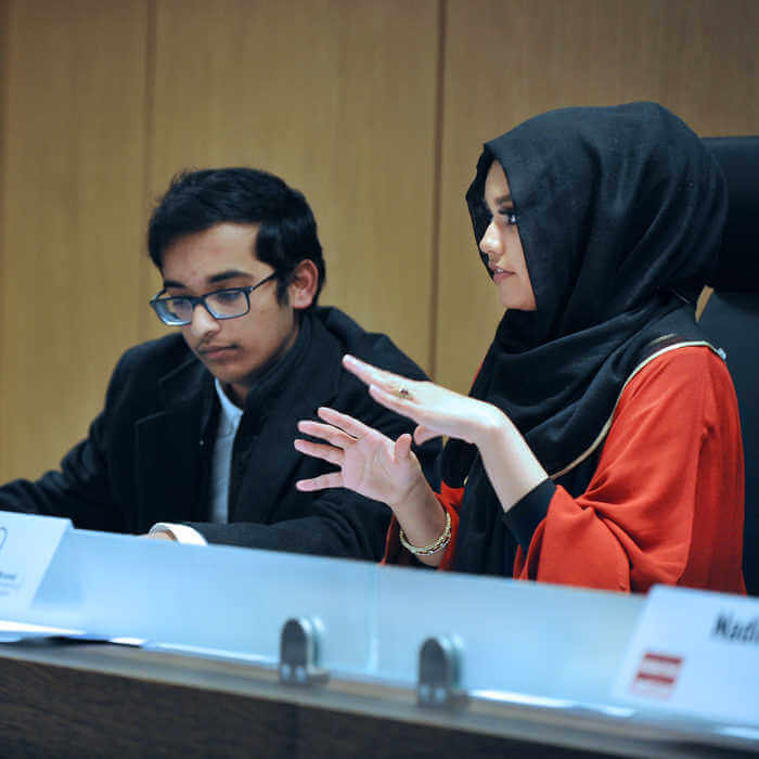 two students sat behind a desk