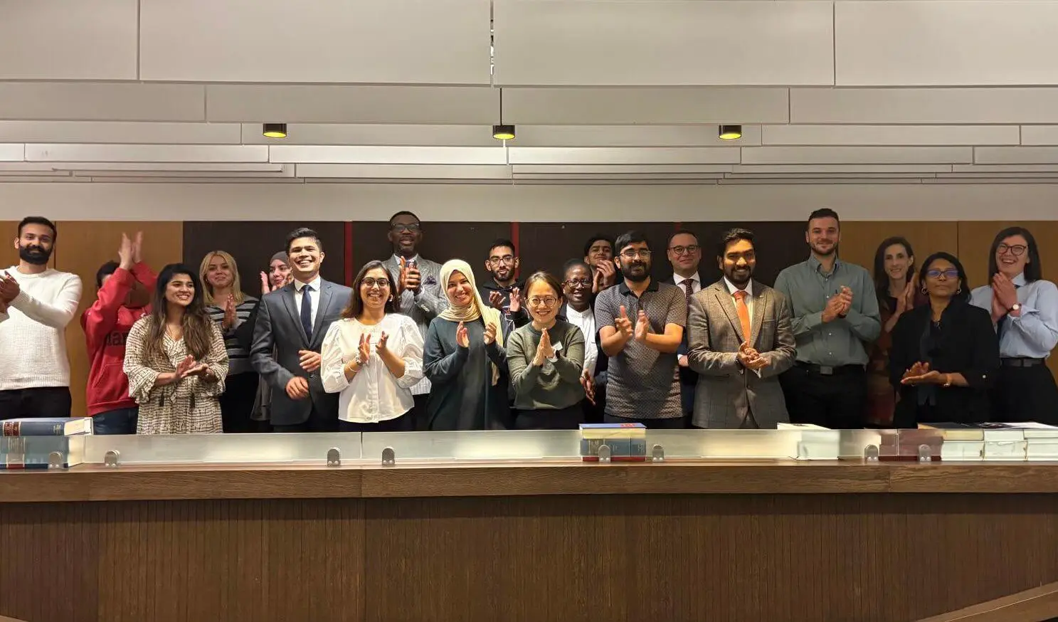 A diverse group of people standing together, applauding joyfully behind a table