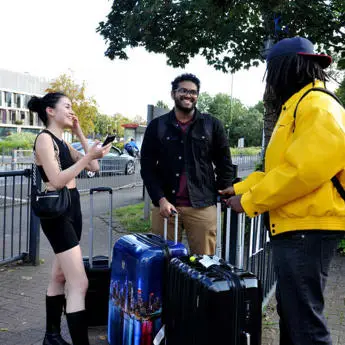 three students with suitcases