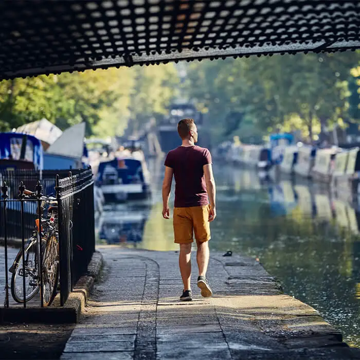 man walking by boats on a canal