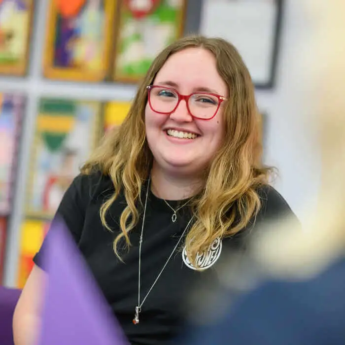 Young woman with red glasses and long blonde hair smiling