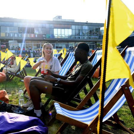 Two students sitting on deck chairs in the green quad area of campus