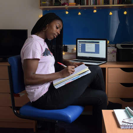 female student sitting in her accommodation room doing some revision