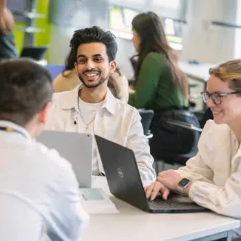 group of students with laptops sitting around a table