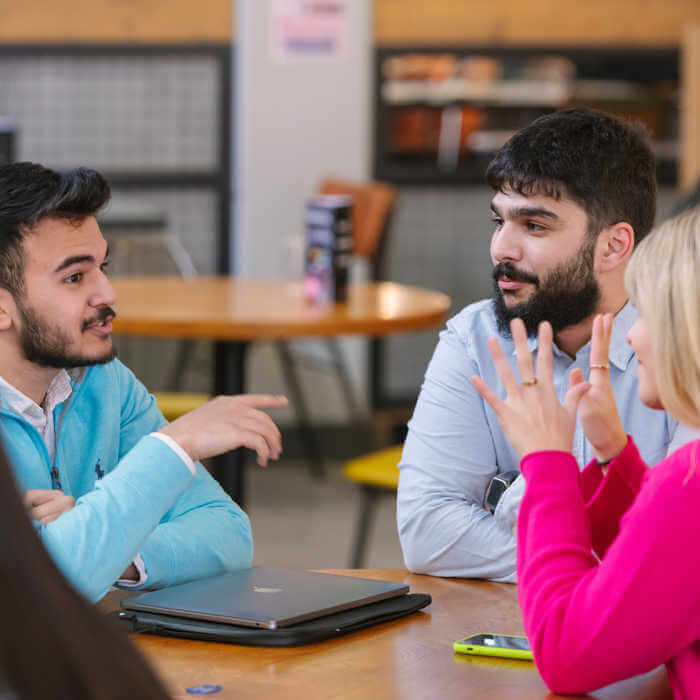 three students chatting around a table