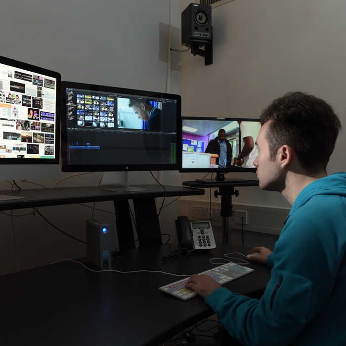 students using media editing software on a computer with multiple screens