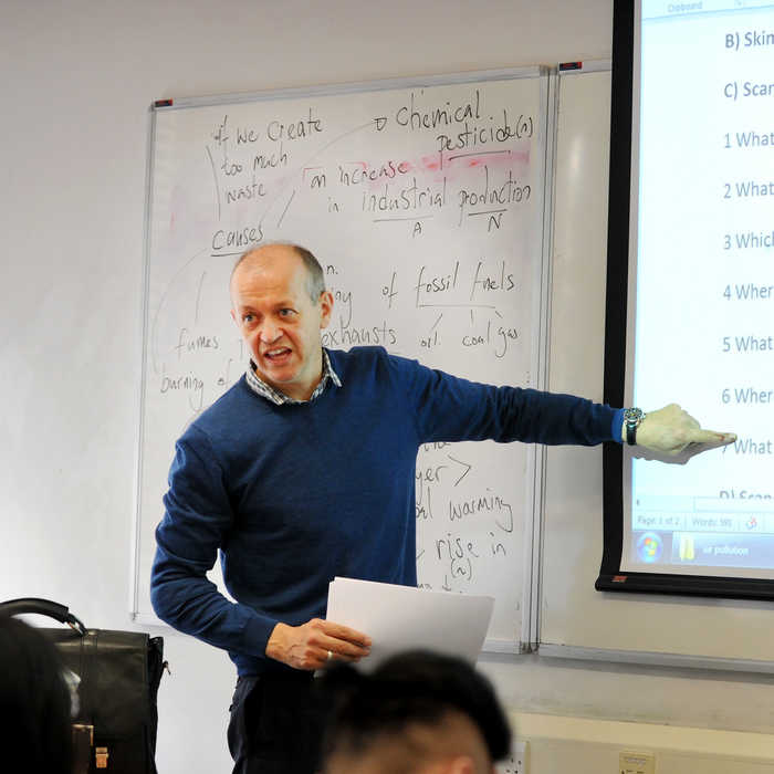 teacher talking to students in classroom and pointing at writing on the white board