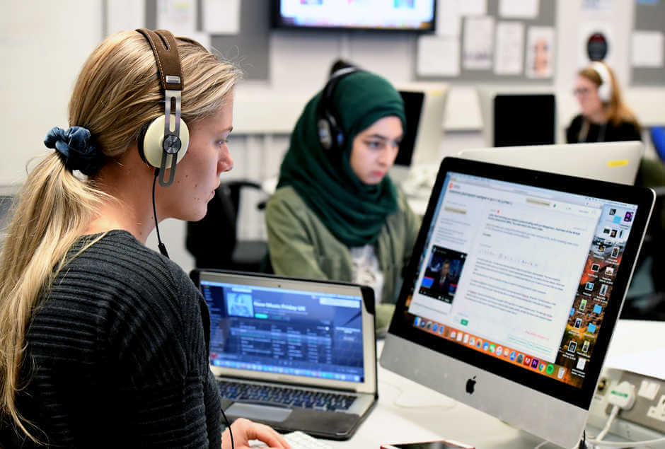 two female students with headsets working on desktops