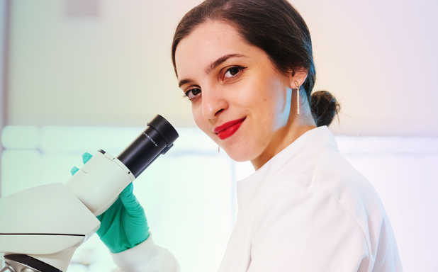 biomedical sciences student in a white coat and a microscope
