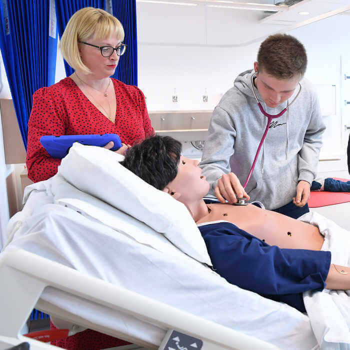 male student using a stethoscope to practise listening to manikins heartbread