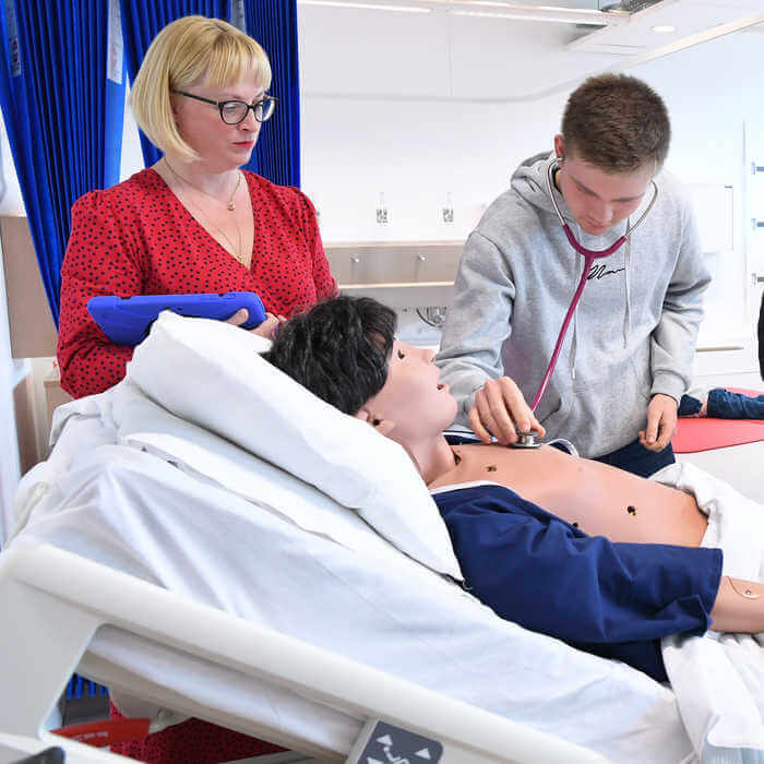 male student using a stethoscope to practise listening to manikins heartbread