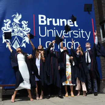 group of graduating students in front of a large Brunel University sign(1)