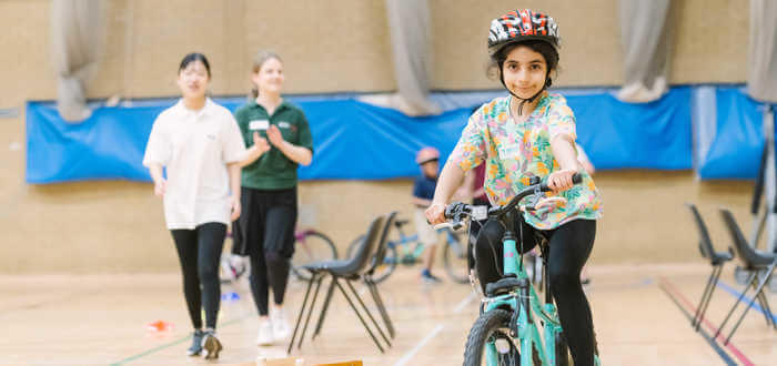 Young girl riding on a pedal bike in a gym